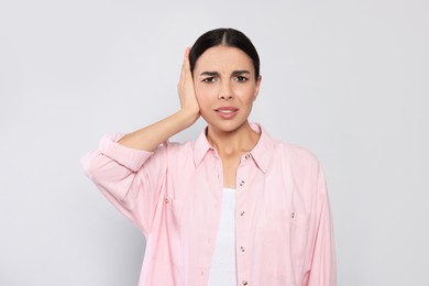 Photo of Young woman suffering from ear pain on light grey background