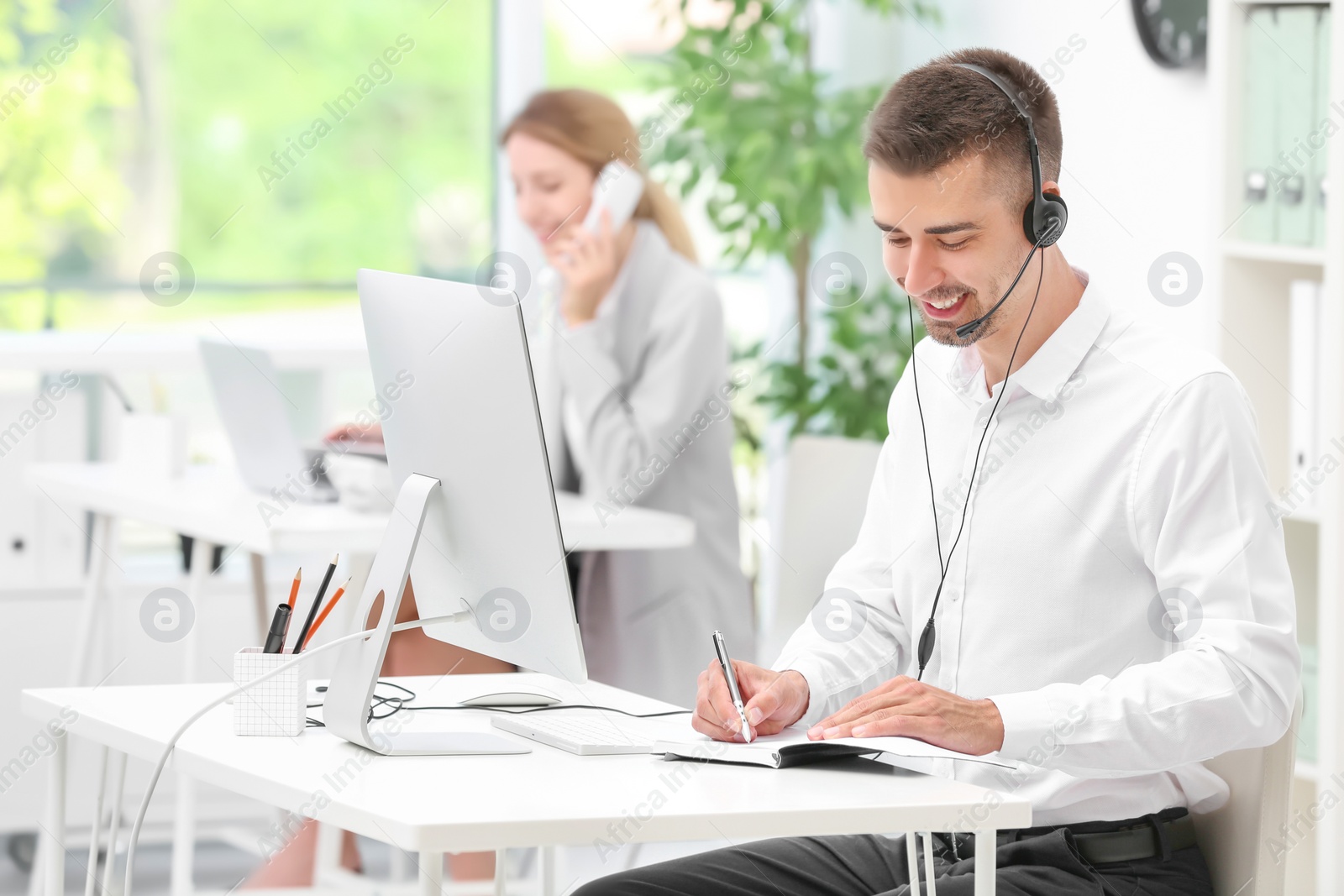 Photo of Male receptionist with headset at desk in office