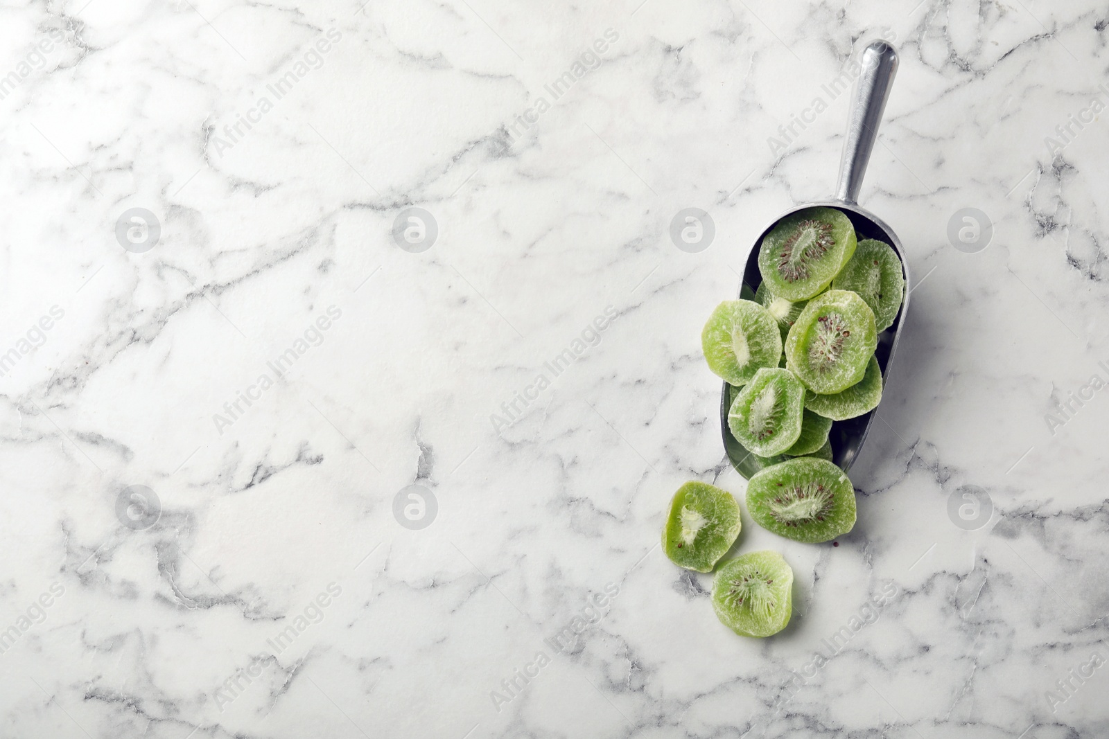 Photo of Scoop of dried kiwi on marble background, top view with space for text. Tasty and healthy fruit