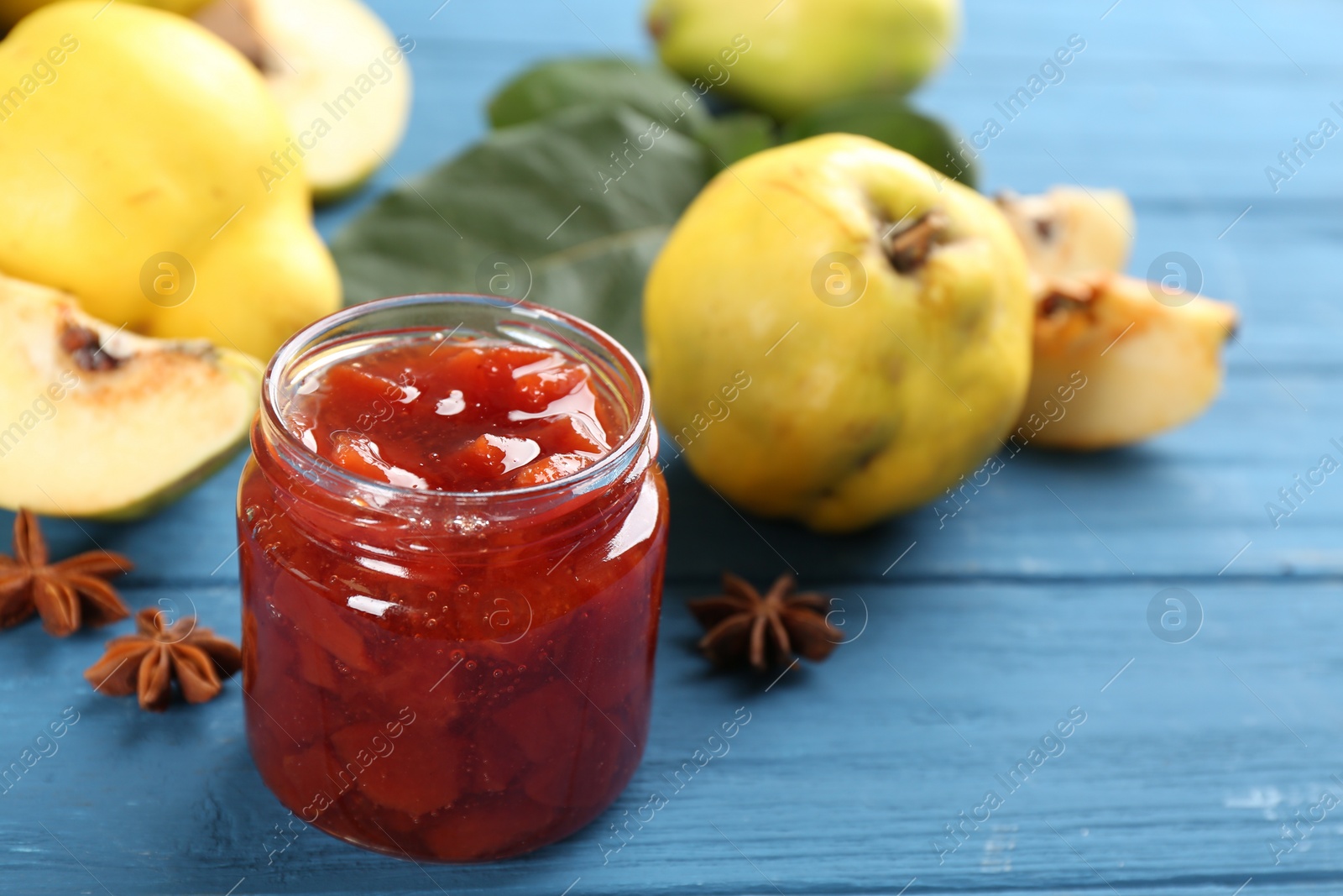Photo of Delicious quince jam on blue wooden table, closeup
