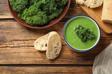 Photo of Tasty kale soup on wooden table, flat lay