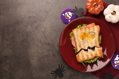 Cute monster sandwich with fried eggs on grey textured table, flat lay and space for text. Halloween snack