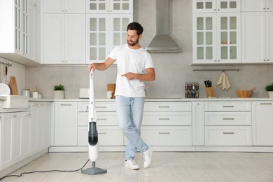 Happy man with steam mop in kitchen at home