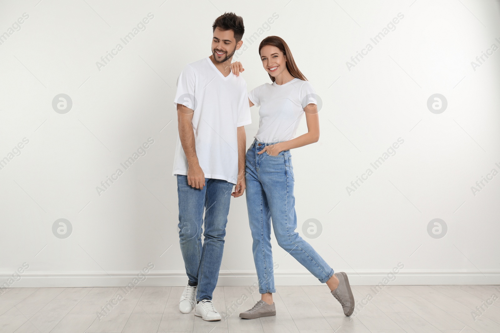 Photo of Young couple in stylish jeans near white wall