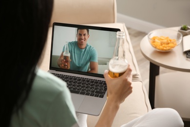 Photo of Friends drinking beer while communicating through online video conference at home. Social distancing during coronavirus pandemic