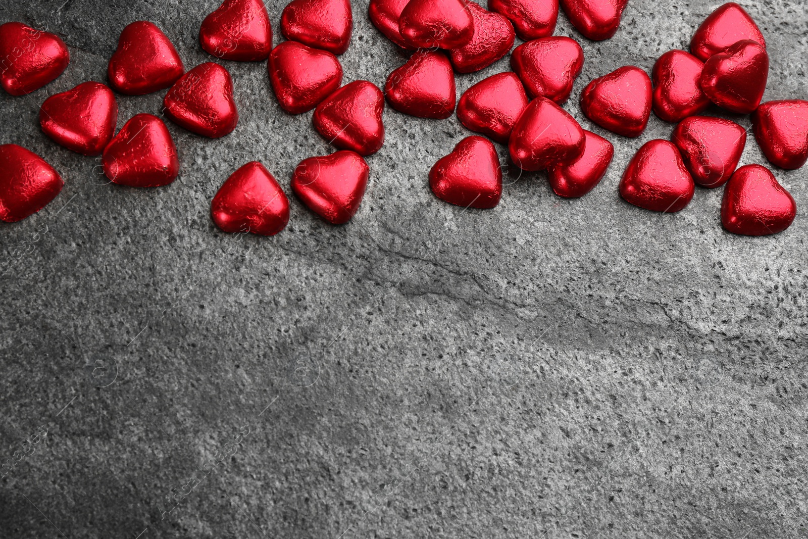 Photo of Heart shaped chocolate candies on grey table, flat lay. Space for text