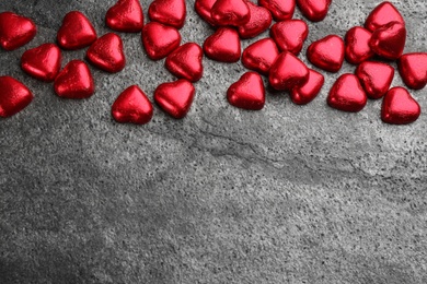 Heart shaped chocolate candies on grey table, flat lay. Space for text