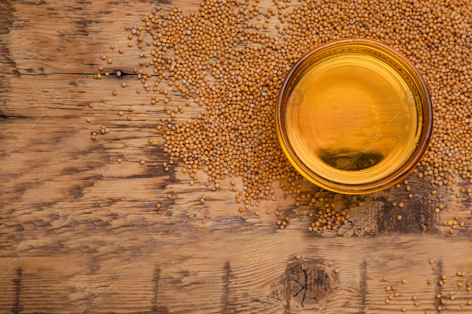 Bowl of natural oil and mustard seeds on wooden table, top view. Space for text Photo of Bowl of natural oil and mustard seeds on wooden table, top view. Space for text