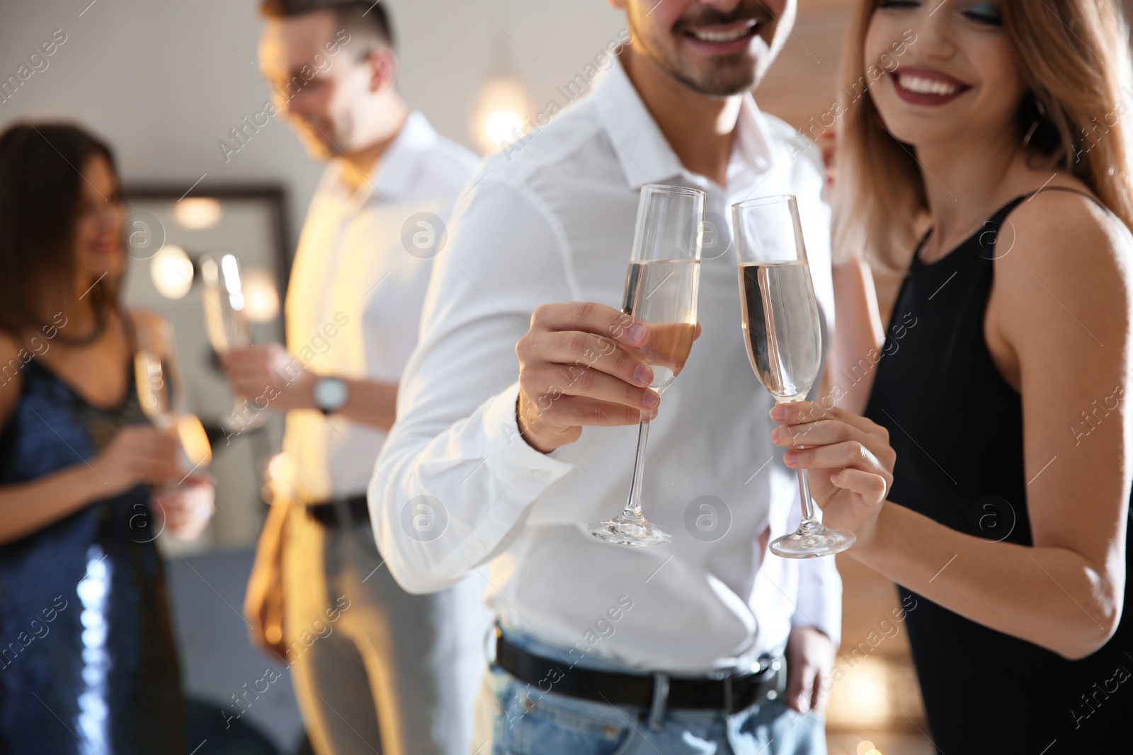 Photo of Couple clinking glasses with champagne at party indoors, closeup