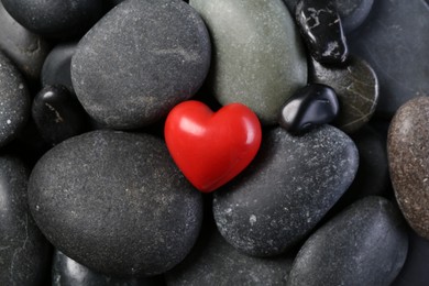 Red decorative heart on pebble stones, top view