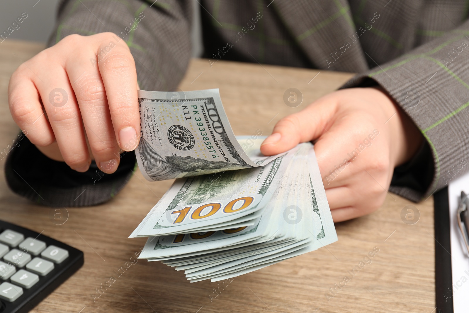 Photo of Money exchange. Woman counting dollar banknotes at wooden table, closeup