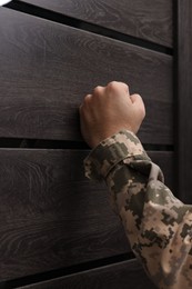 Photo of Military commissariat representative knocking on wooden door, closeup