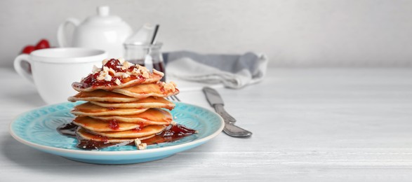 Delicious pancakes with jam and nuts served for breakfast on table, space for text. Banner design