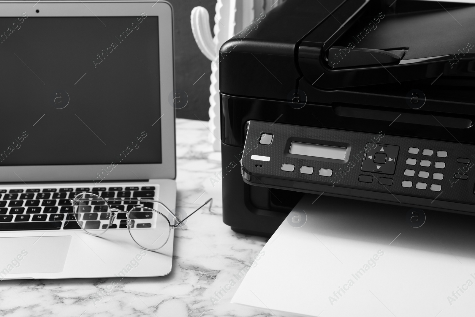 Photo of Modern printer, laptop and glasses on white marble table