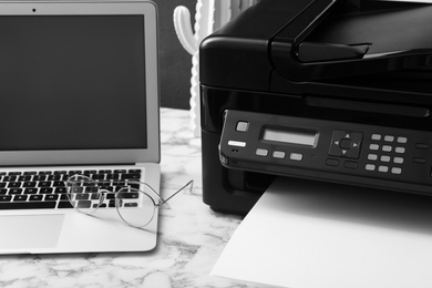 Modern printer, laptop and glasses on white marble table