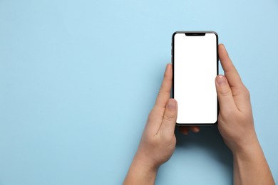 Photo of Woman with smartphone on light blue background, top view. Space for text