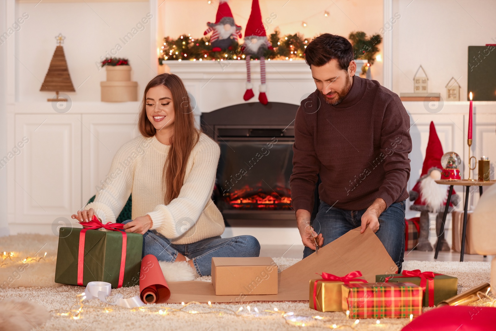 Photo of Happy couple decorating Christmas gifts at home