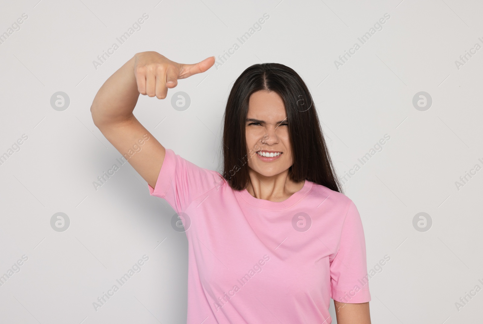 Photo of Aggressive young woman pointing on light grey background