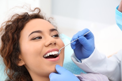 Photo of Dentist examining African-American woman's teeth in hospital