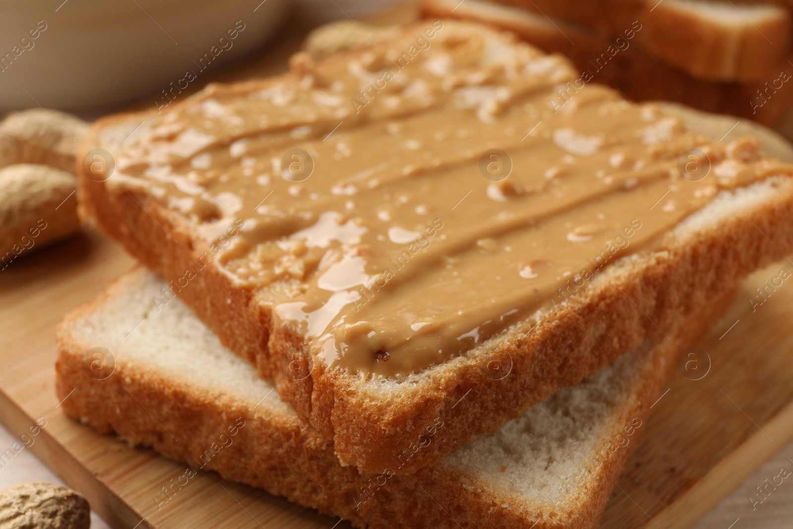 Photo of Delicious toasts with peanut butter on table, closeup