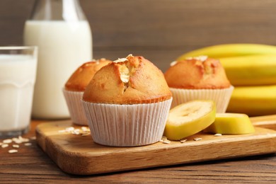 Tasty muffins served with banana on wooden table