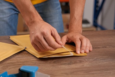 Post office worker with adhesive paper bag at counter indoors, closeup