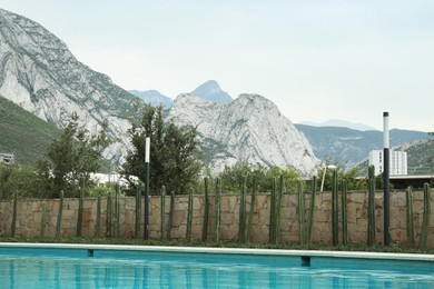 Photo of Outdoor swimming pool surrounded by cactuses and mountains on background