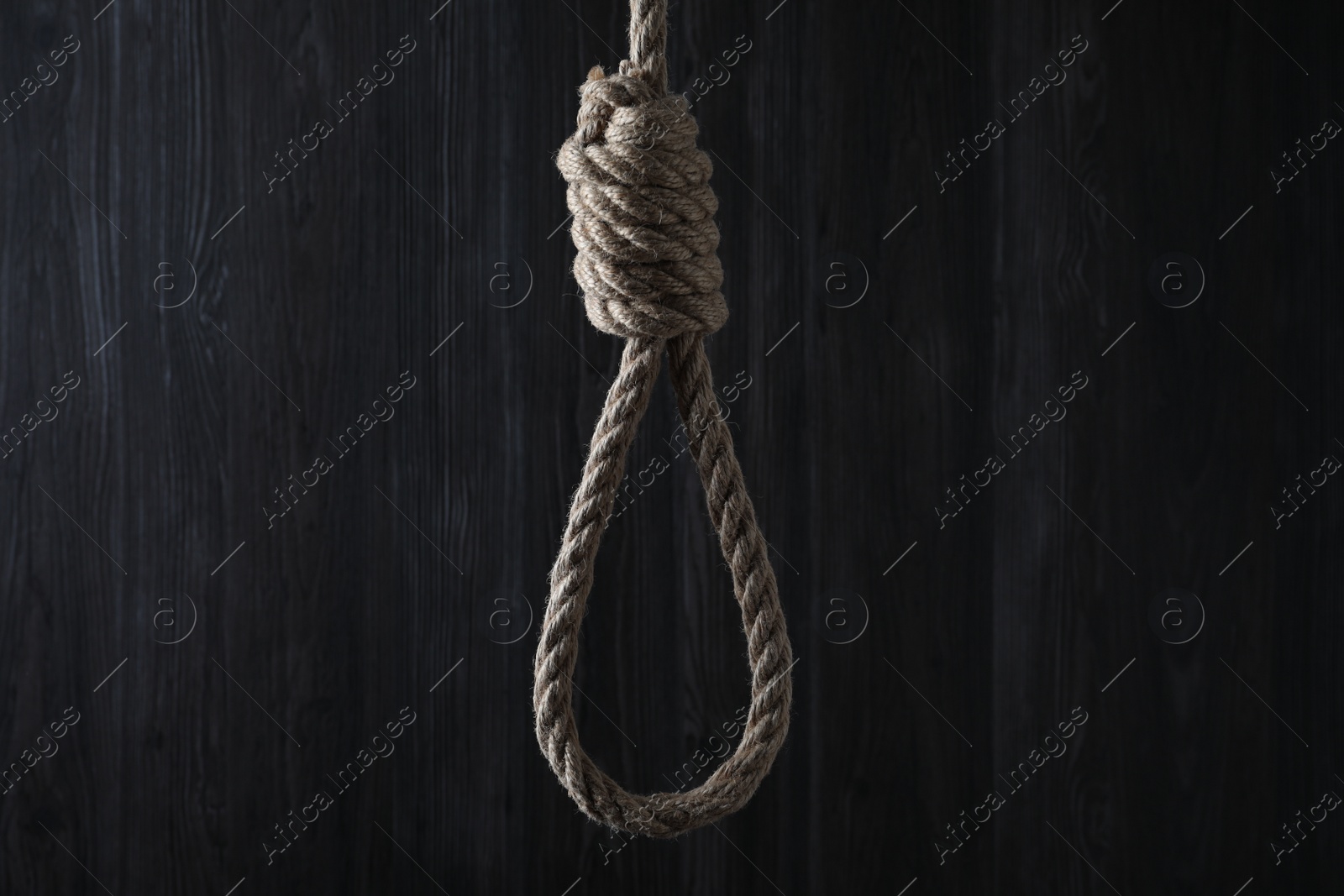 Photo of Tied rope noose against dark wooden background