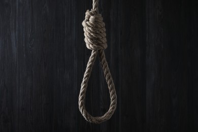 Photo of Tied rope noose against dark wooden background