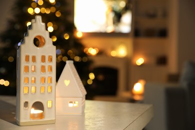 Beautiful house shaped candle holders on table indoors, space for text. Bokeh effect