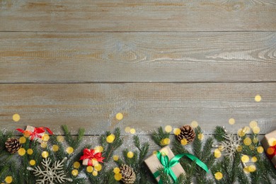 Photo of Christmas greeting card with space for text. Flat lay composition of fir tree branches and festive decor on wooden background