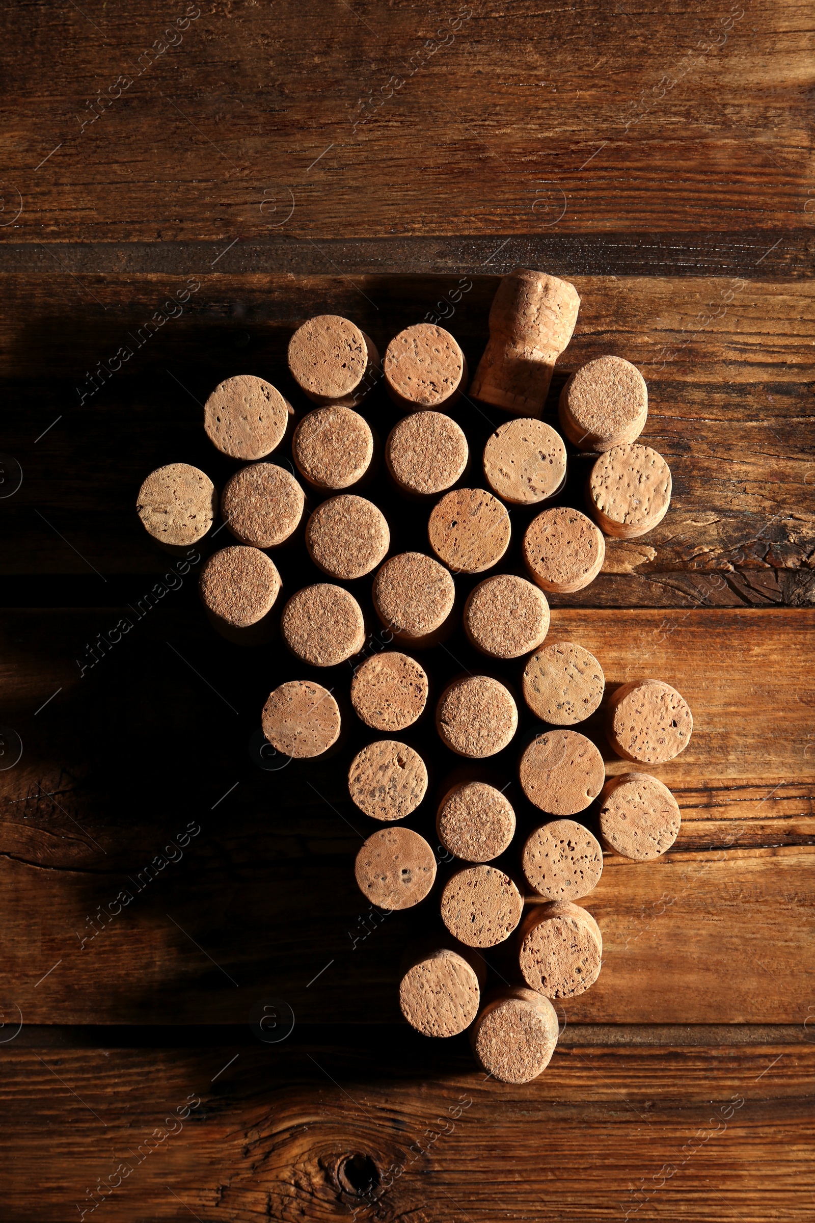 Photo of Grape made of wine bottle corks on wooden table, top view