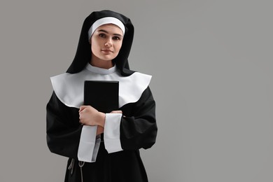 Photo of Nun with Bible on grey background, space for text