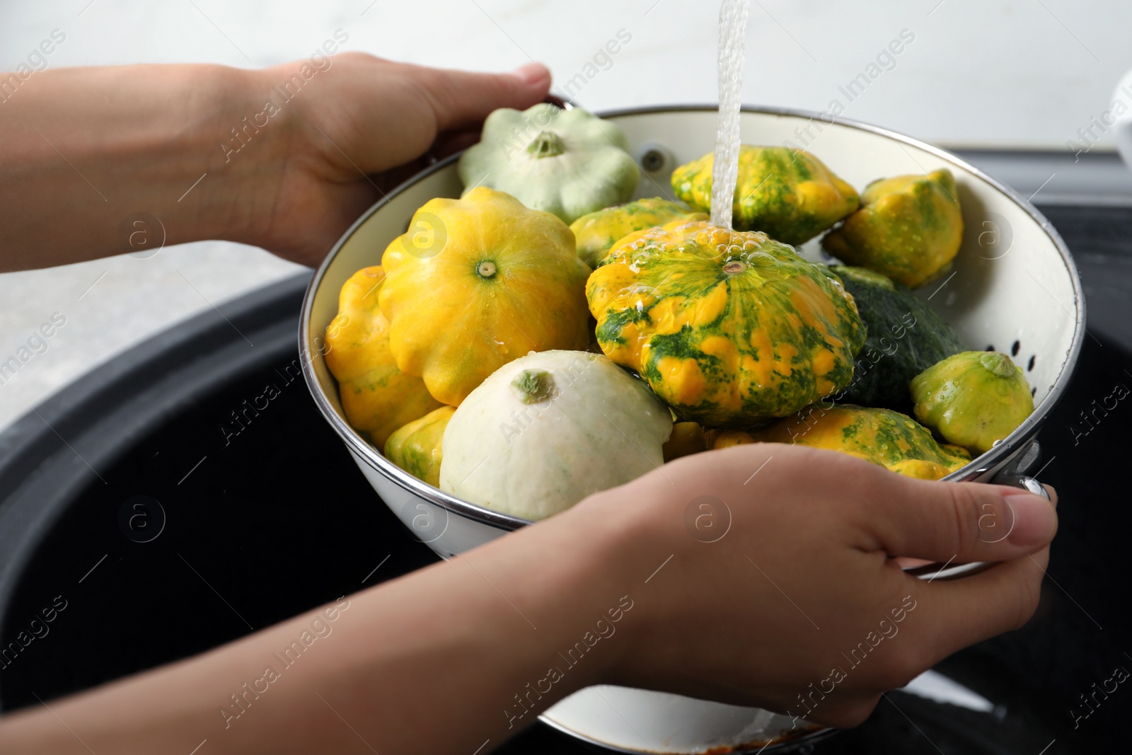 Photo of Woman washing pattypan squashes above sink, closeup