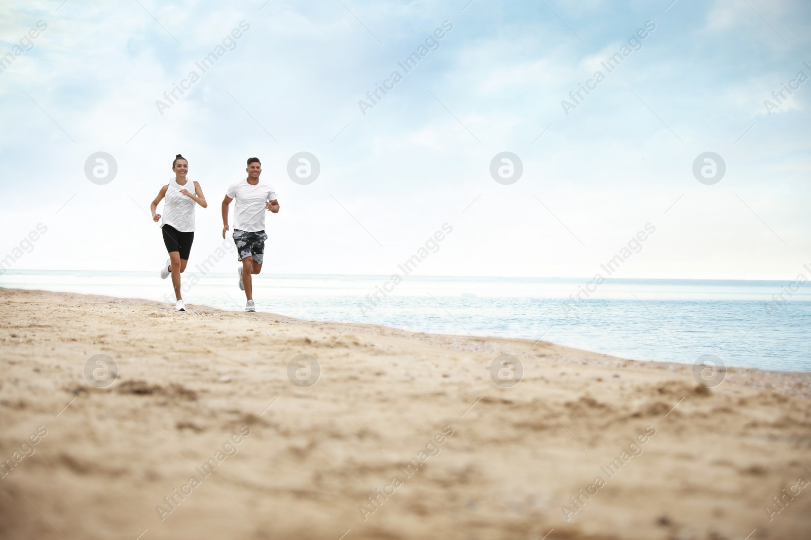 Photo of Couple running together on beach, space for text. Body training