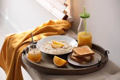 Photo of Wooden tray with delicious breakfast on bench indoors