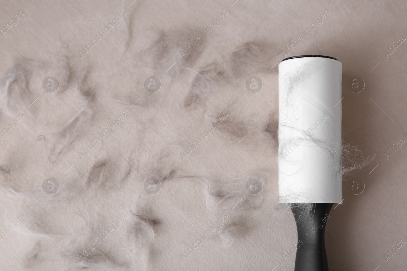 Photo of Modern lint roller and cat hair on light fabric, flat lay