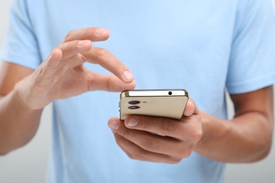 Photo of Young man sending message via smartphone on light grey background, closeup