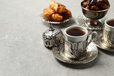 Photo of Tea, baklava dessert and date fruits served in vintage tea set on grey table, space for text