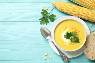 Photo of Delicious creamy corn soup served on turquoise wooden table, flat lay. Space for text