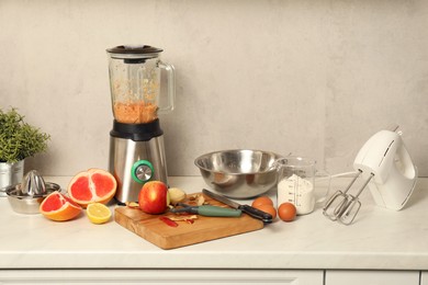 Photo of Modern mixer, blender and different ingredients on white marble countertop