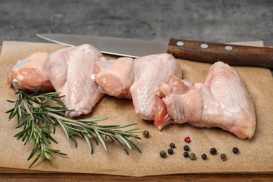 Photo of Board with raw chicken wings and spices on table, closeup. Fresh meat