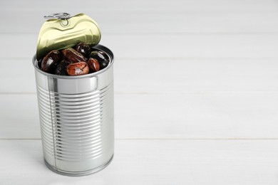 Photo of Tin can with kidney beans on white wooden table, space for text