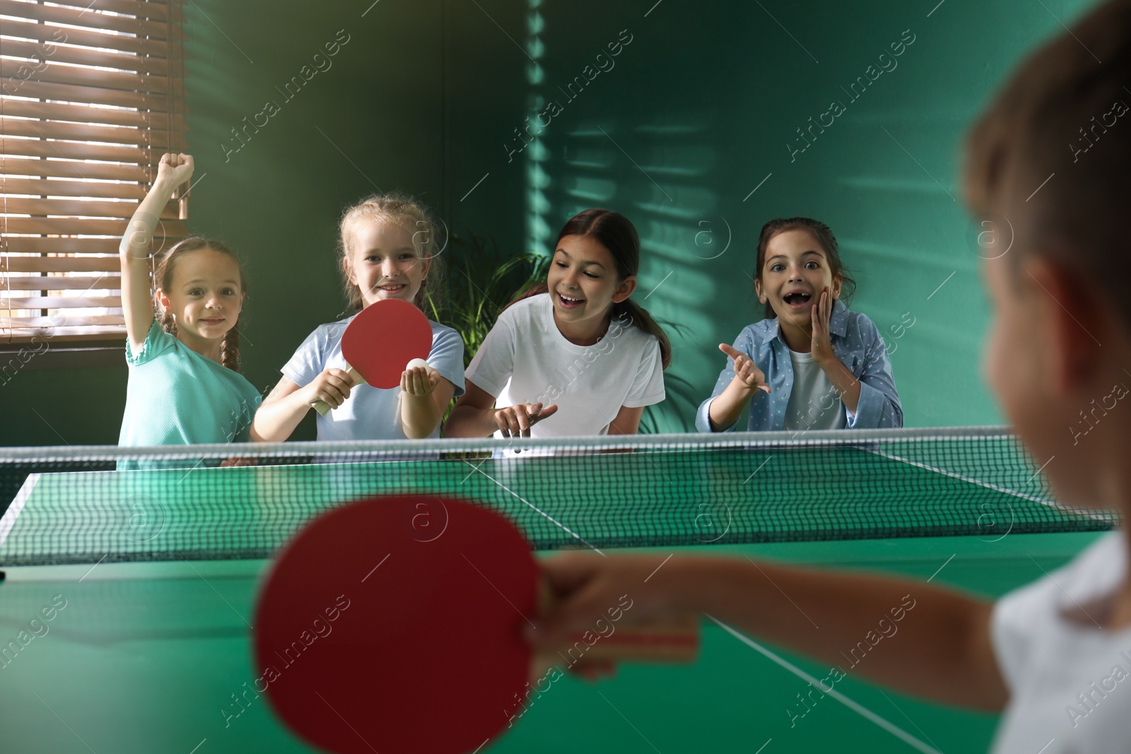 Photo of Cute happy children playing ping pong indoors