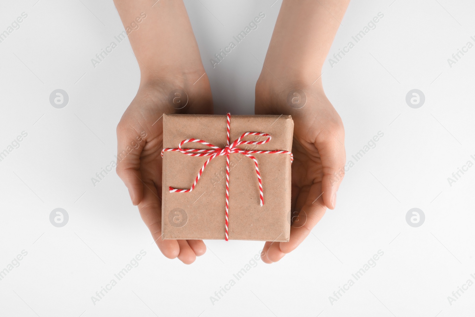 Photo of Woman holding parcel wrapped in kraft paper on white background, top view