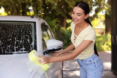 Photo of Smiling woman washing auto with sponge at outdoor car wash