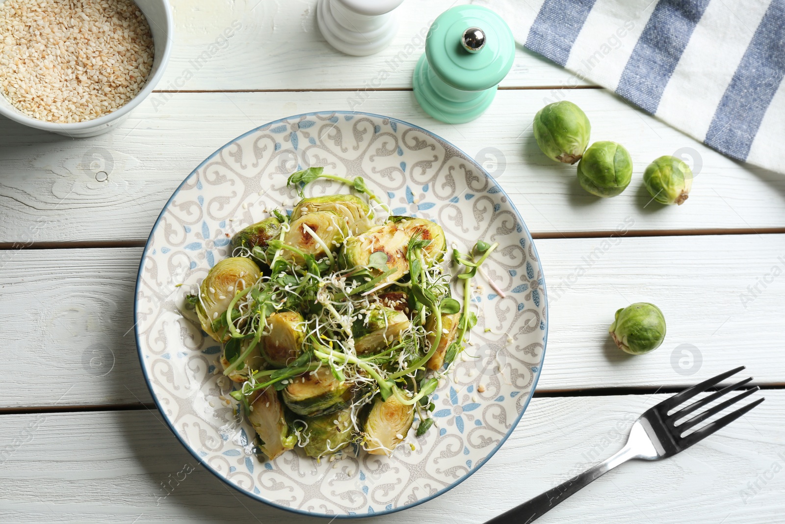 Photo of Delicious salad with roasted Brussels sprouts on white wooden table, flat lay