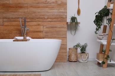 White tub and beautiful plants in bathroom, Interior design