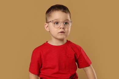 Photo of Cute little boy in glasses on pale brown background