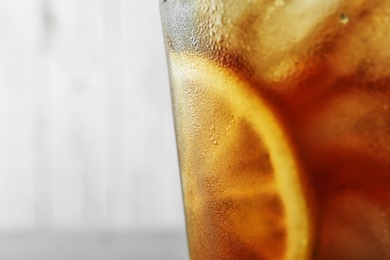 Glass of refreshing iced tea against light background, closeup. Space for text